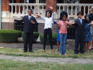 A group of people are dancing in front of a brick building