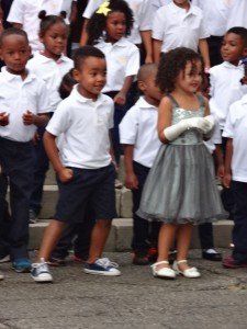 A girl in a grey dress is standing in front of a group of children