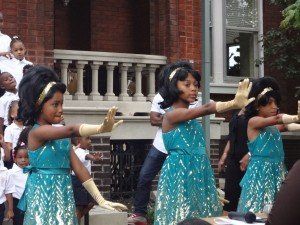 A group of young girls are dancing in front of a brick building