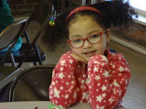 A little girl wearing glasses is sitting at a table