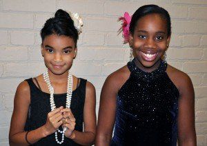 Two girls are posing for a picture and one has a flower in her hair