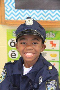 A young boy dressed as a police officer smiles for the camera