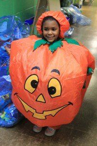 A little girl is dressed in a pumpkin costume.