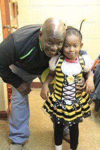 A man is standing next to a little girl in a bee costume