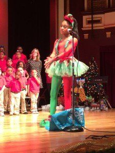 A girl dressed as an elf is singing into a microphone