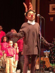 A young girl in a reindeer costume is singing into a microphone.