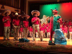 A group of children are standing on a stage in front of a microphone.