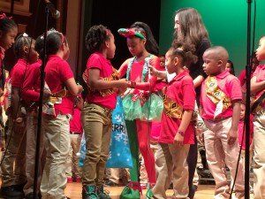 A group of children are standing on a stage talking to each other.
