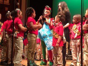 A group of children are standing in front of microphones on a stage.