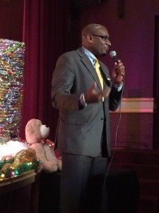 A man in a suit and tie is speaking into a microphone