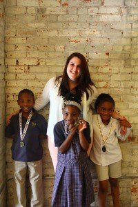 A woman and three children are posing for a picture in front of a brick wall.