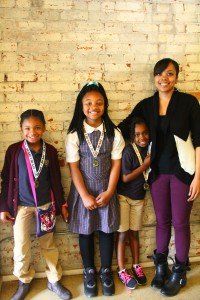 A group of children are posing for a picture in front of a brick wall.
