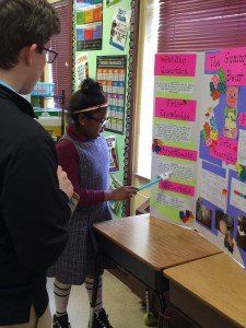 A boy and a girl are looking at a project in a classroom.