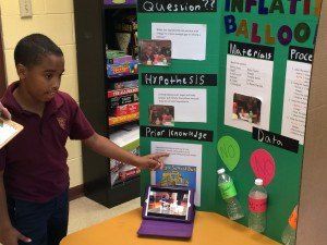 A young boy is standing in front of a balloon project board