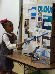 A little girl is standing in front of a poster that says clouds