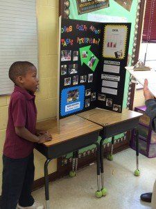 A young boy is standing in front of a display board that says 