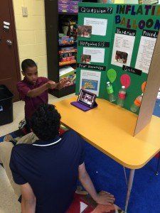 A boy is sitting at a table with a sign that says inflatable balloons