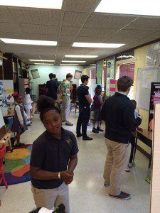 A group of people are standing in a hallway in a classroom.