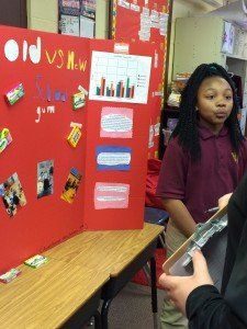 A girl is standing in front of a red board that says old vs new