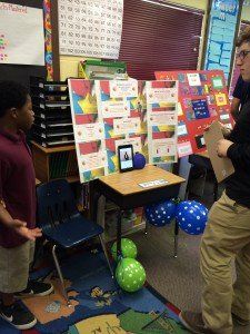 A group of children are standing in a classroom with balloons on the floor.