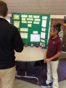 A boy and a girl are standing in front of a green board