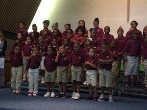 A large group of children are standing on a stage.