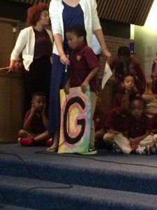 A little boy holding a sign with the letter g on it