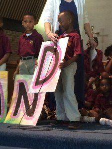 A boy is holding a microphone in front of a sign that says dn