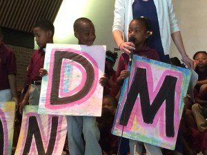 A group of children are holding up signs that say dm and nm