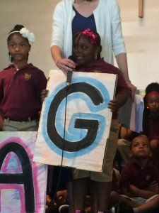 A girl holding a sign with the letter g on it
