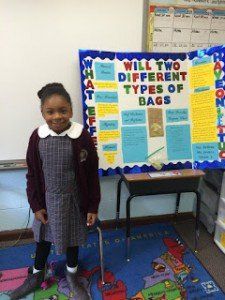 A little girl is standing in front of a board that says will two different types of bags