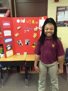 A young girl is standing in front of a red board that says old vs new