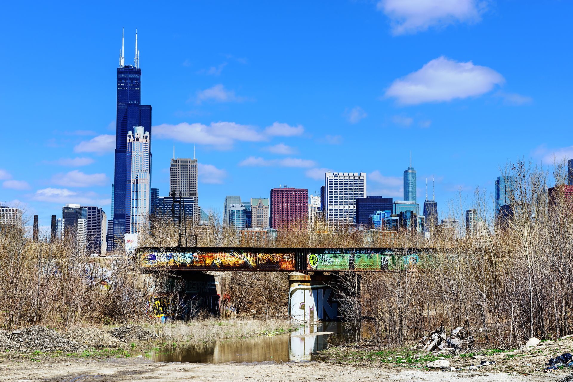 A bridge with graffiti on it in front of a city skyline.