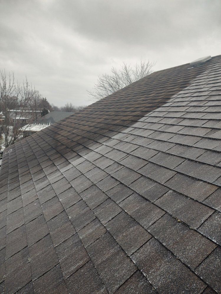 A black and white photo of a roof with a cloudy sky in the background.