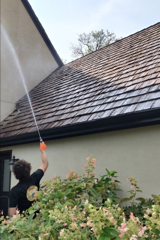 A person is cleaning a wooden deck with a high pressure washer.