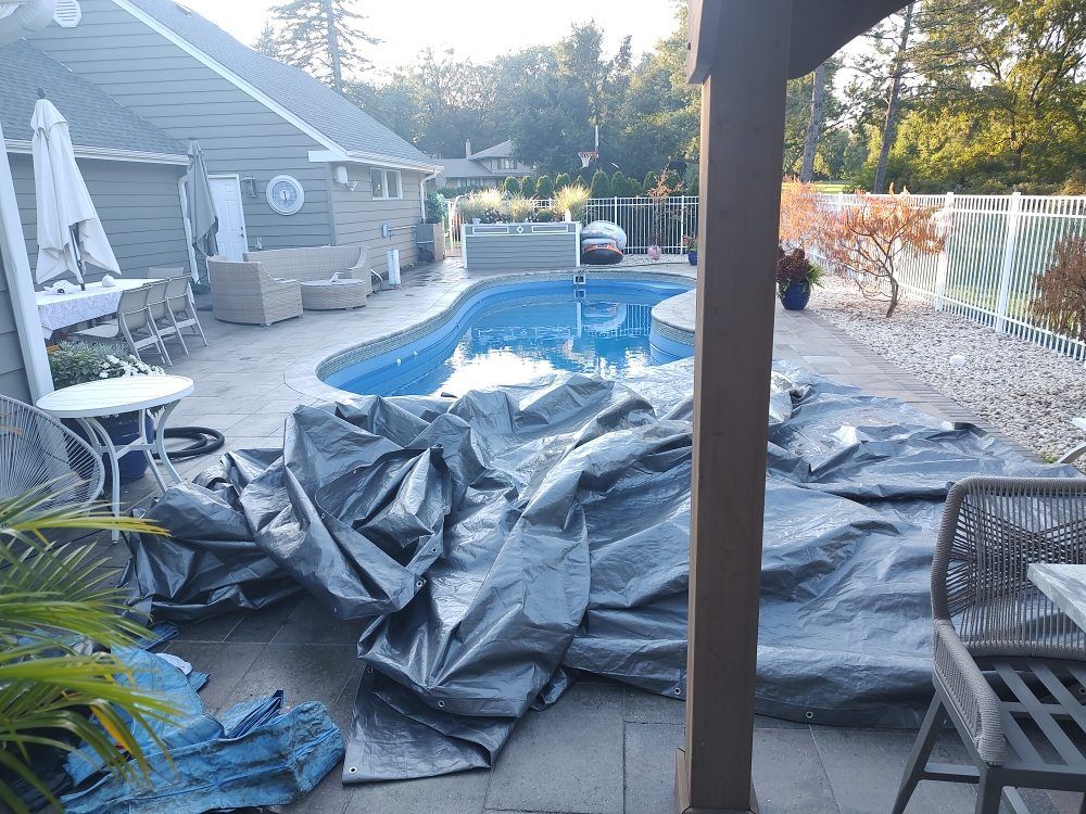 A swimming pool is being built in a backyard with tarps on the ground.
