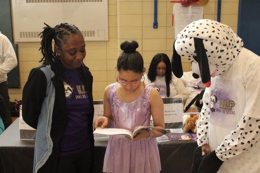 A girl is reading a book next to a dalmatian mascot