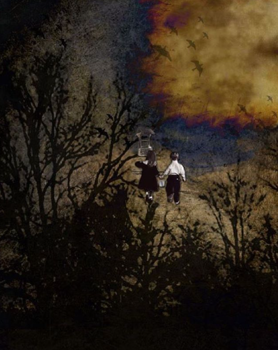 A man and a woman are walking in a field with a fire in the background.