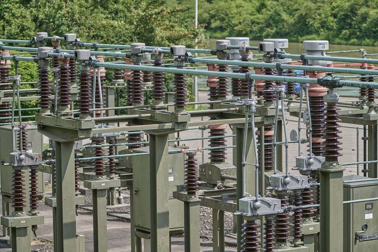 Electrical substation with tall insulators and metal conductors, outdoors.