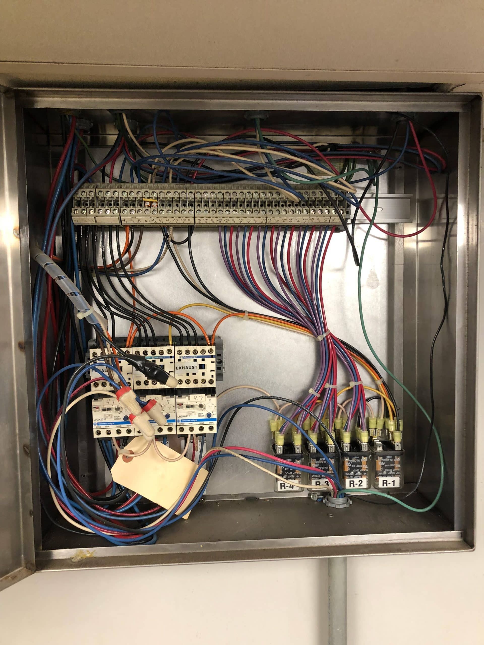 Metal electrical panel with numerous colored wires and circuit components.