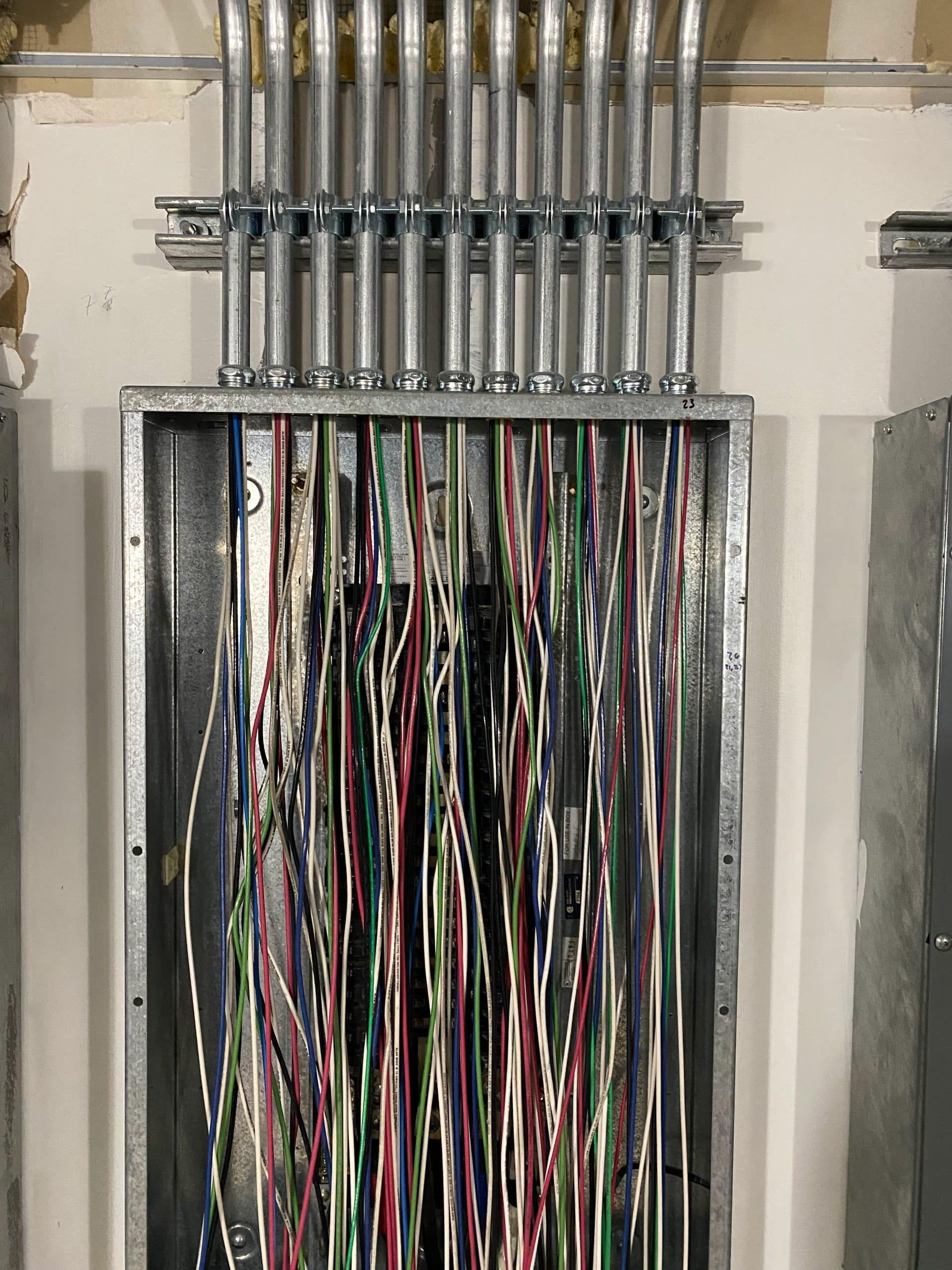 Electrical wiring within a metal junction box, with multiple conduits and colored wires.