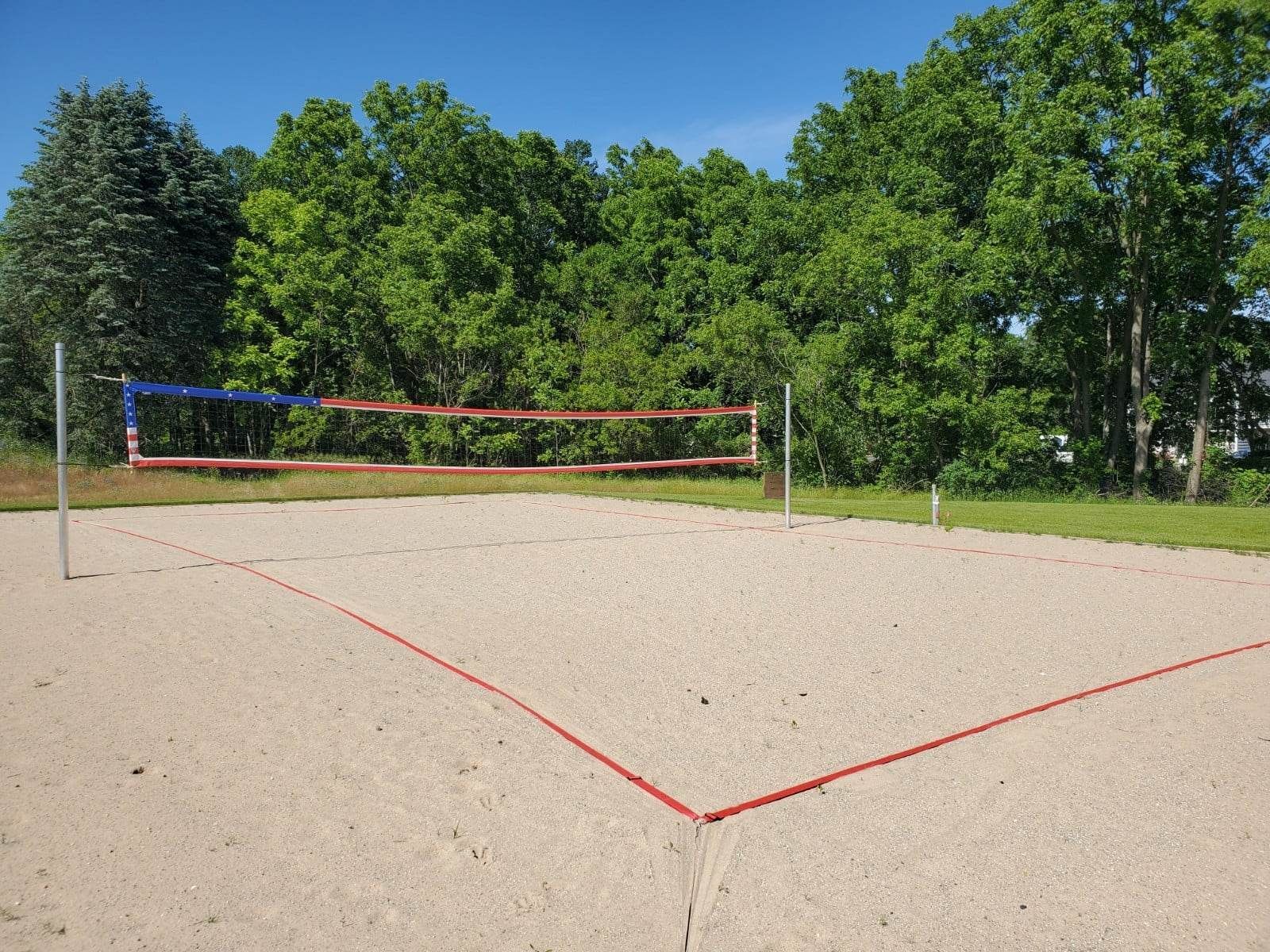 A sand volleyball court with trees in the background