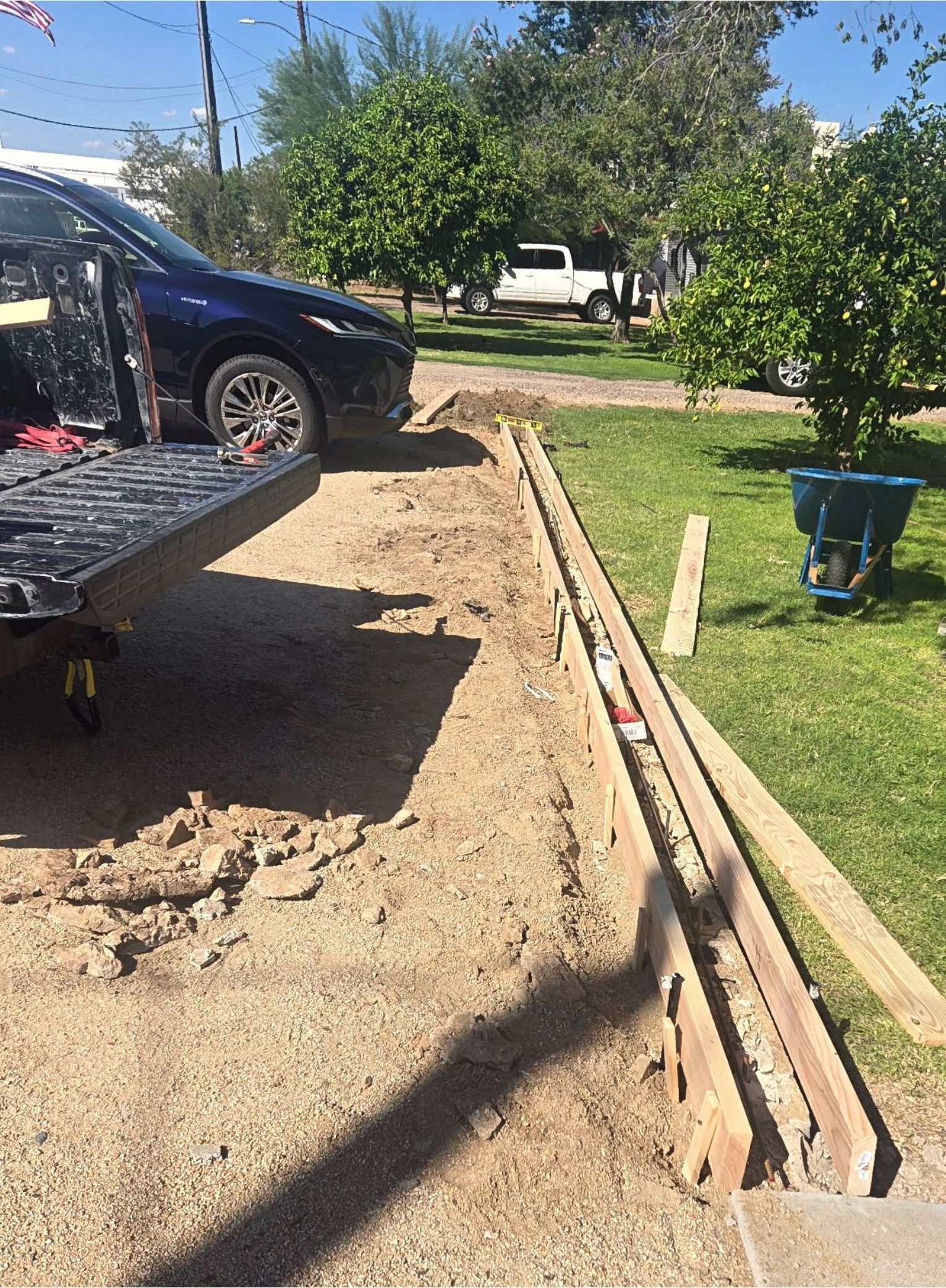 A truck bed open next to a trench along a grass lawn; construction in progress outdoors.
