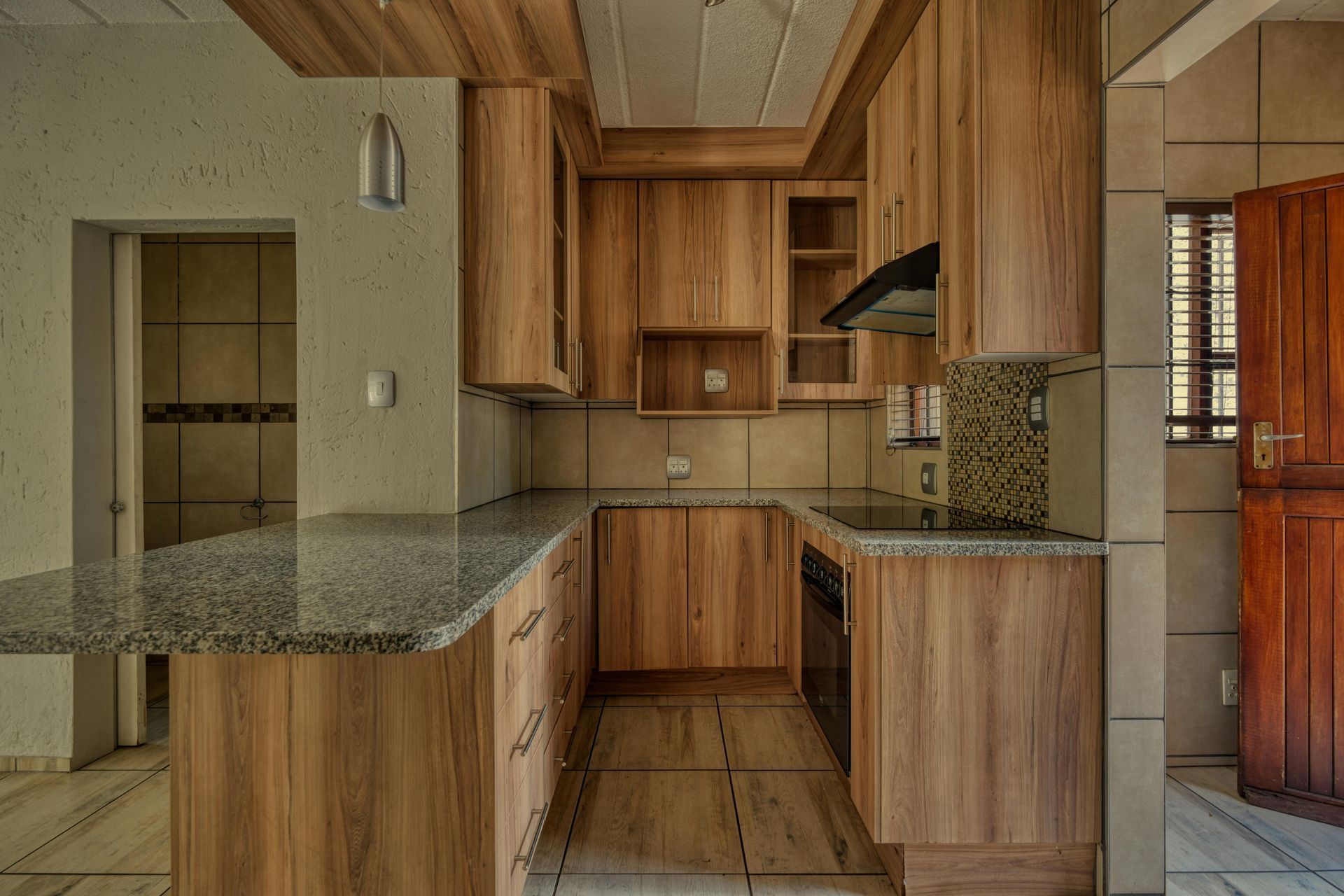 Kitchen with light wood cabinets, granite countertops, and a built-in oven.