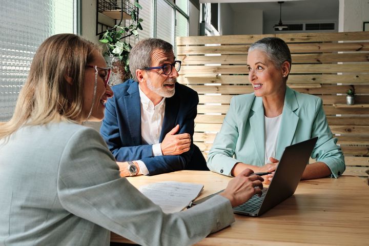 A group of people are sitting at a table with a laptop.
