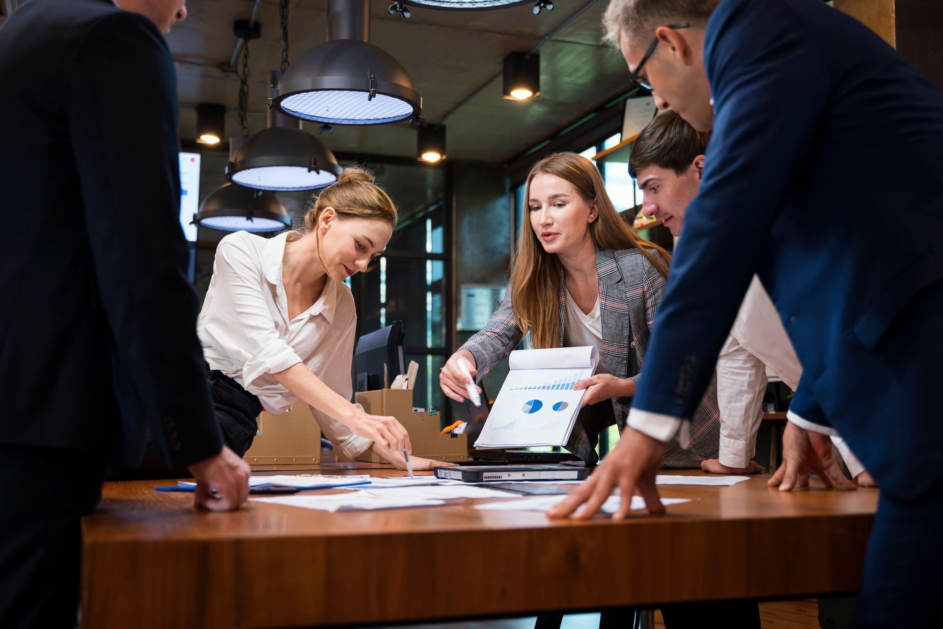A group of people are standing around a table looking at papers.