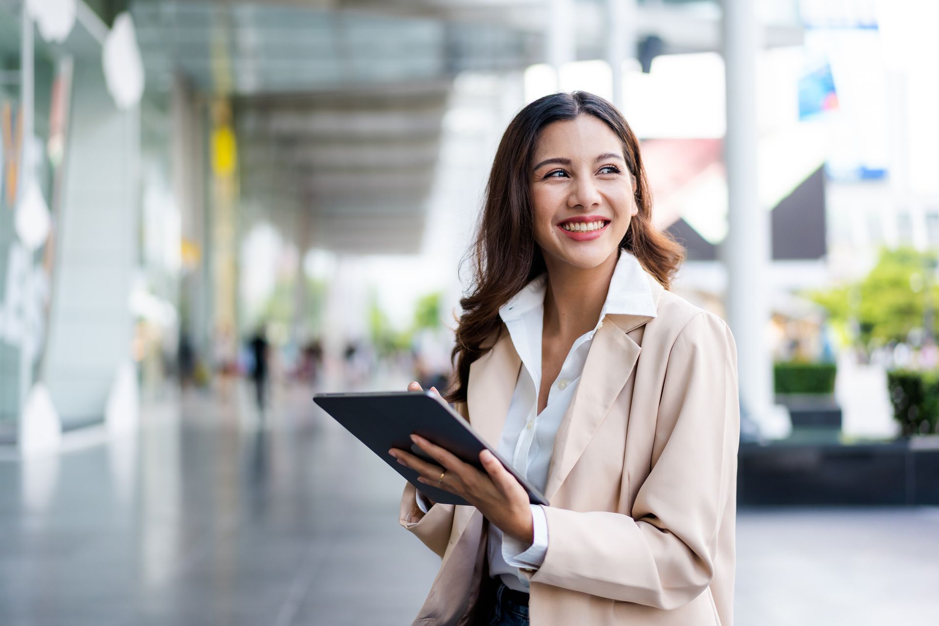 A woman is holding a tablet in her hand and smiling.