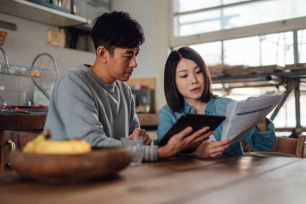 A man and a woman are sitting at a table looking at a tablet.