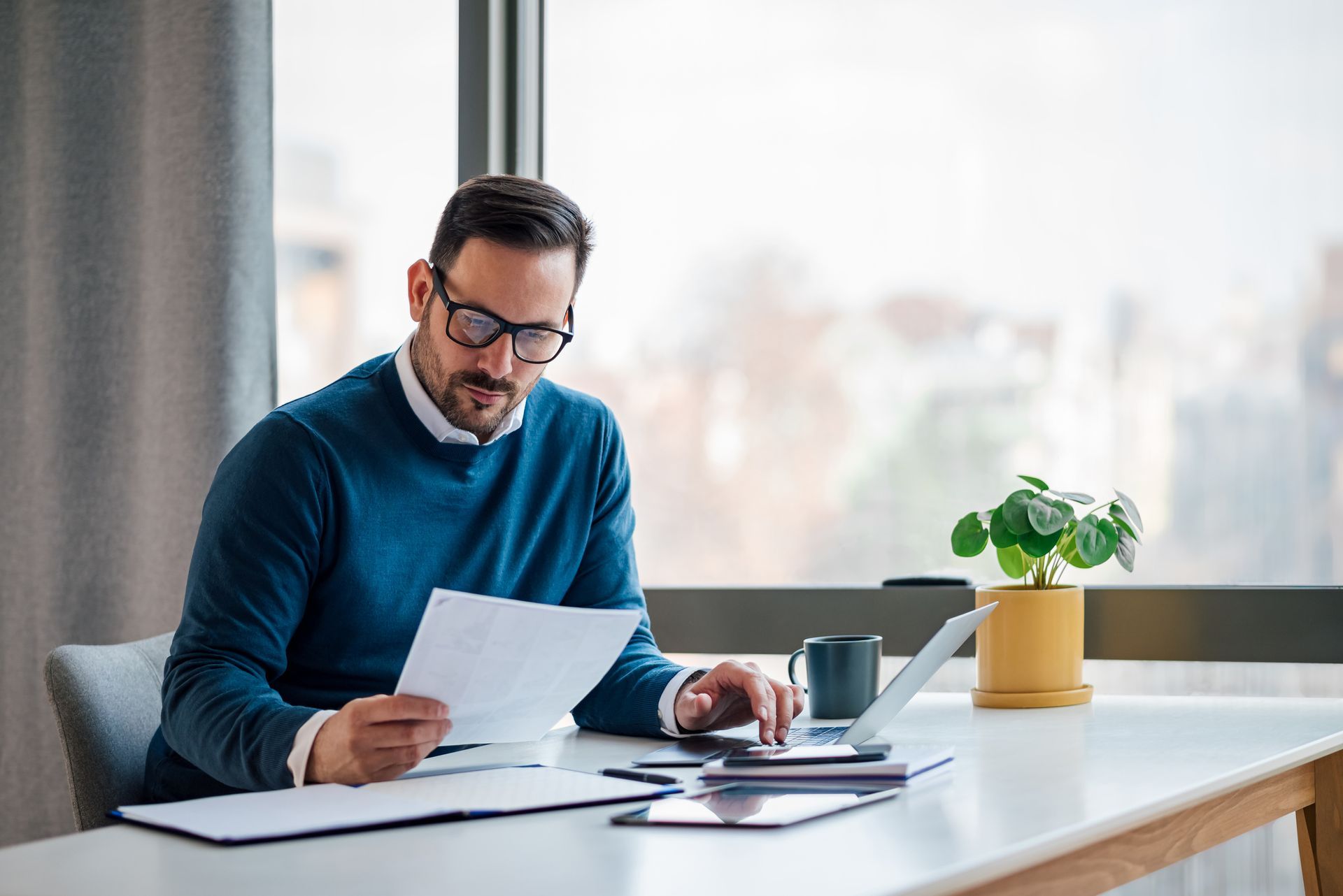 A man is sitting at a desk looking at a paper.
