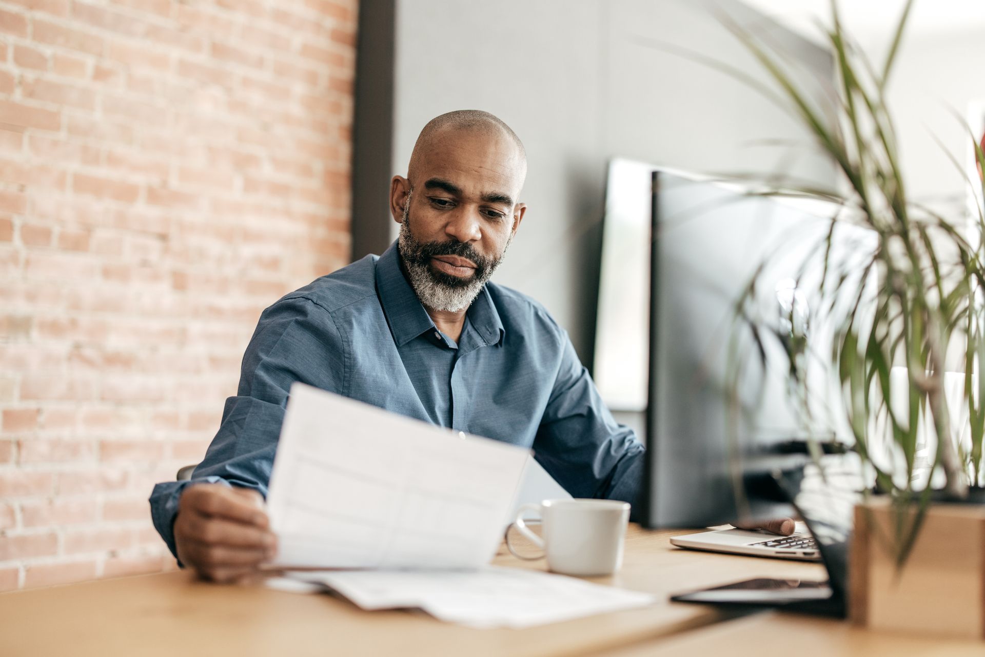 A man is sitting at a desk looking at a piece of paper.